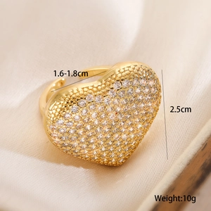 Macro detail of gold-plated heart ring with pavé zircons on champagne satin background