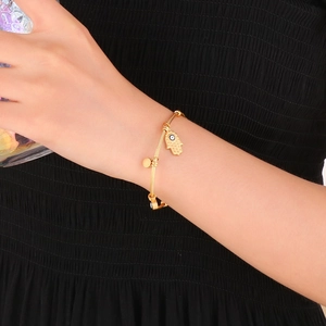 Hamsa Hand evil eye charm bracelet in 18K gold stainless steel on a model's wrist