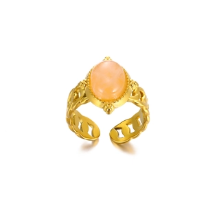 Macro detail of vintage 18K gold-plated ring featuring an oval orange gemstone and hollow band