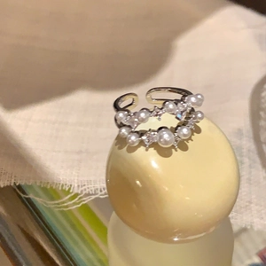Dettaglio dell'anello ondulato a doppio strato con perle bianche e accenti in zircone