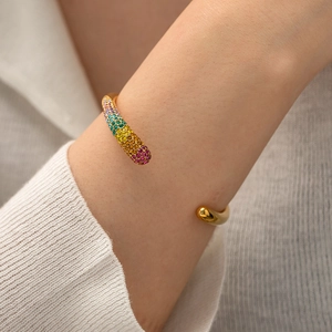 Close-up of 18K gold-plated open cuff bracelet featuring multi-colored gemstone inlays