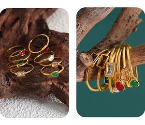 Detailed set of minimalist gold rings with emerald and ruby glass stones on rustic wood