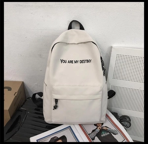 Sac à dos en toile blanc avec slogan 'You Are My Destiny' posé sur une valise noire