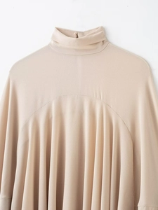 Close-up of beige high-neck blouse with subtle texture and rear collar button detail