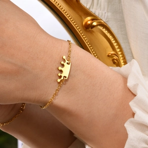 Elegant gold crown charm bracelet on minimalist fine chain with a vintage frame background