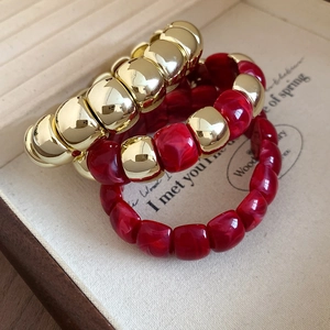 Macro detail of acrylic square beads with gold mirror finish and deep red marble textures