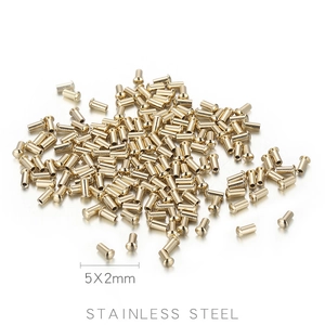 Macro shot of 5x2mm golden stainless steel rivets piled on a light grey surface