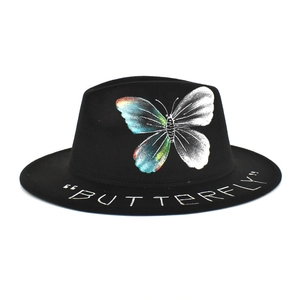 Detail of colorful butterfly print and handwritten text on a black wool fedora hat