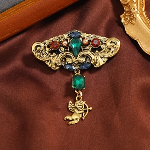 Vintage Baroque emerald brooch with Cupid pendant on brown satin backdrop