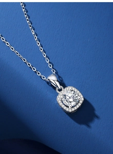 Macro detail of a 1.25ct square moissanite pendant on a silver chain over blue background