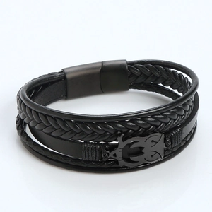 Close-up of black braided leather bracelet featuring a metal owl charm and magnetic clasp