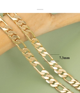 Detail shot of 7.3mm gold-plated Figaro link chain on a wooden stand with 18K finish