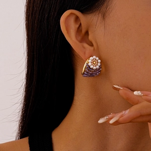 Detailed close-up of retro floral stud earrings with white pearls and purple bead clusters