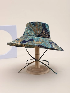 Close-up of tropical palm leaf print on a wide-brim sun hat with matching chin strap