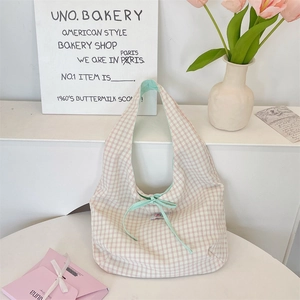 Detail of plaid fabric shoulder bag with mint green ribbon bow and woven label