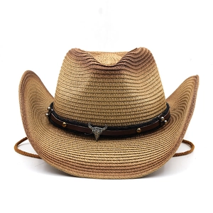 Detail of western straw hat featuring leather band with metallic bull skull and studs