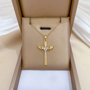 Detailed view of luxury gold wing cross necklace with crystals in a champagne jewelry box