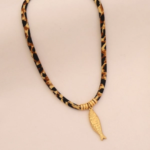 Detail of leopard print cord necklace with a textured golden fish pendant close-up