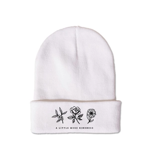 Detail of white knit beanie featuring three floral patterns and kindness text