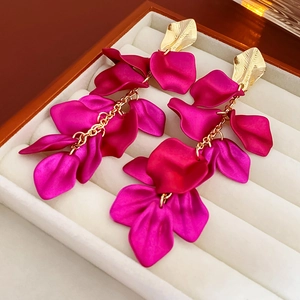 Détail de boucles d'oreilles pétales rouge rose et clous feuilles dorées sur boîte