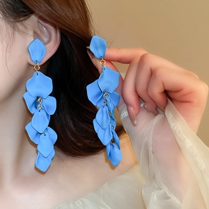 Detail of blue petal tassel clip earrings with matte texture and golden finish on model