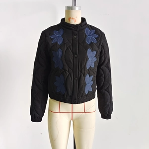 Detail of black quilted jacket featuring blue floral embroidery and stand collar