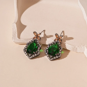 Close-up of vintage drop earrings featuring green pear-cut stones and crystal details