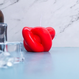 Bougie parfumée moderne en forme de nœud rouge sur marbre avec des glaçons décoratifs
