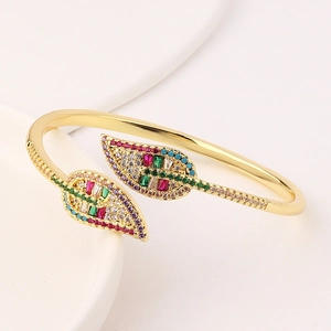 Elegant gold-plated leaf bangle with colorful zircon stones on a white stand