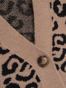 Macro detail of V-neckline and amber button on leopard print knit cardigan