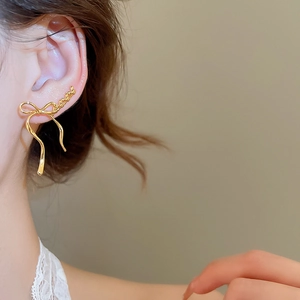 Detail of elegant gold bow earring on model, showcasing refined ribbon curves and texture