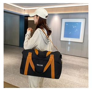 Side view of multi-functional black travel bag with orange details on male model