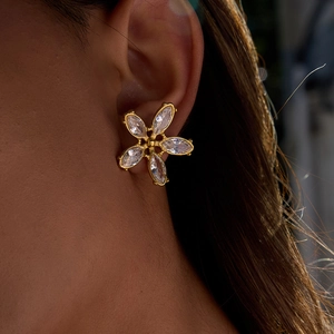 Gros plan de boucles d'oreilles fleur en acier doré 18K avec zircons blancs sur l'oreille