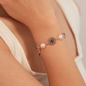 Gros plan du bracelet tournesol en or rose avec perles et cristaux sur le poignet