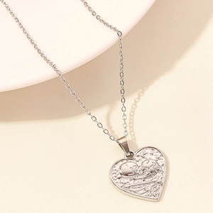 Detail of silver heart pendant featuring skeleton kiss relief and celestial moon elements