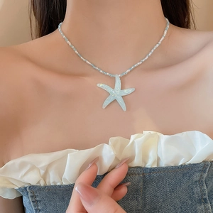 Close-up of light blue resin starfish pendant and beaded necklace worn by a model