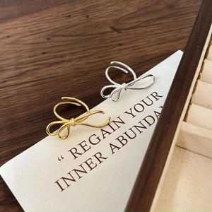 Minimalist 925 sterling silver bow rings in gold and silver set on a wooden gift box