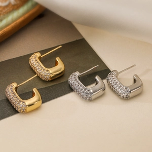 U-shaped gold and silver earrings with cubic zirconia on silk background