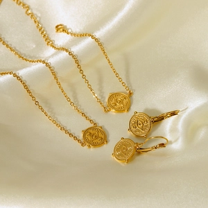 Gold Evil Eye jewelry set including bracelets and earrings on elegant beige silk background