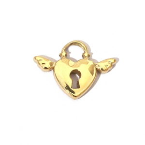 Macro shot of a golden heart lock pendant with wings and polished metallic surface