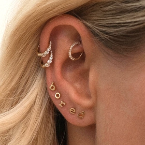 Macro shot of S925 sterling silver gold earrings set with bored letter studs and crystals