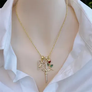 18K gold plated necklace with cross, rose and heart pendants worn on a white shirt