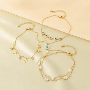 Ensemble de bracelets dorés avec mauvais œil, croix et perles sur tissu beige