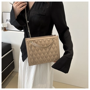 Detail of quilted chain handbag in khaki leather, shown at a 45-degree angle on a model