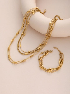 Close-up of gold layered paperclip chain necklace and beaded bracelet jewelry set