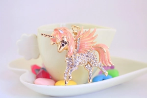 Détail d'un porte-clés licorne avec ailes en émail rose et strass blancs sur une tasse