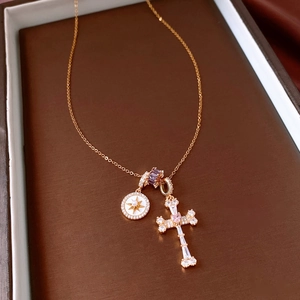 Dettaglio collana croce placcata oro 18k con gemma cuore rosa e disco stella con perla