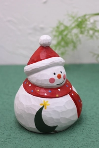 Detail of hand-carved wooden snowman ornament with red hat and painted Christmas tree