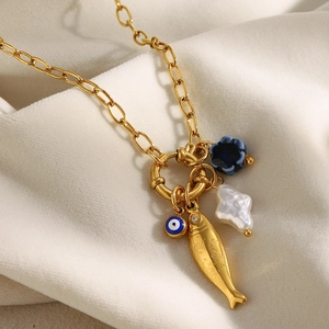 Detailed macro view of 18K gold plated necklace with fish, evil eye, and pearl charms