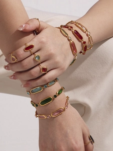 Close-up of stacked gold-plated bracelets and rings with colorful Czech glass stones